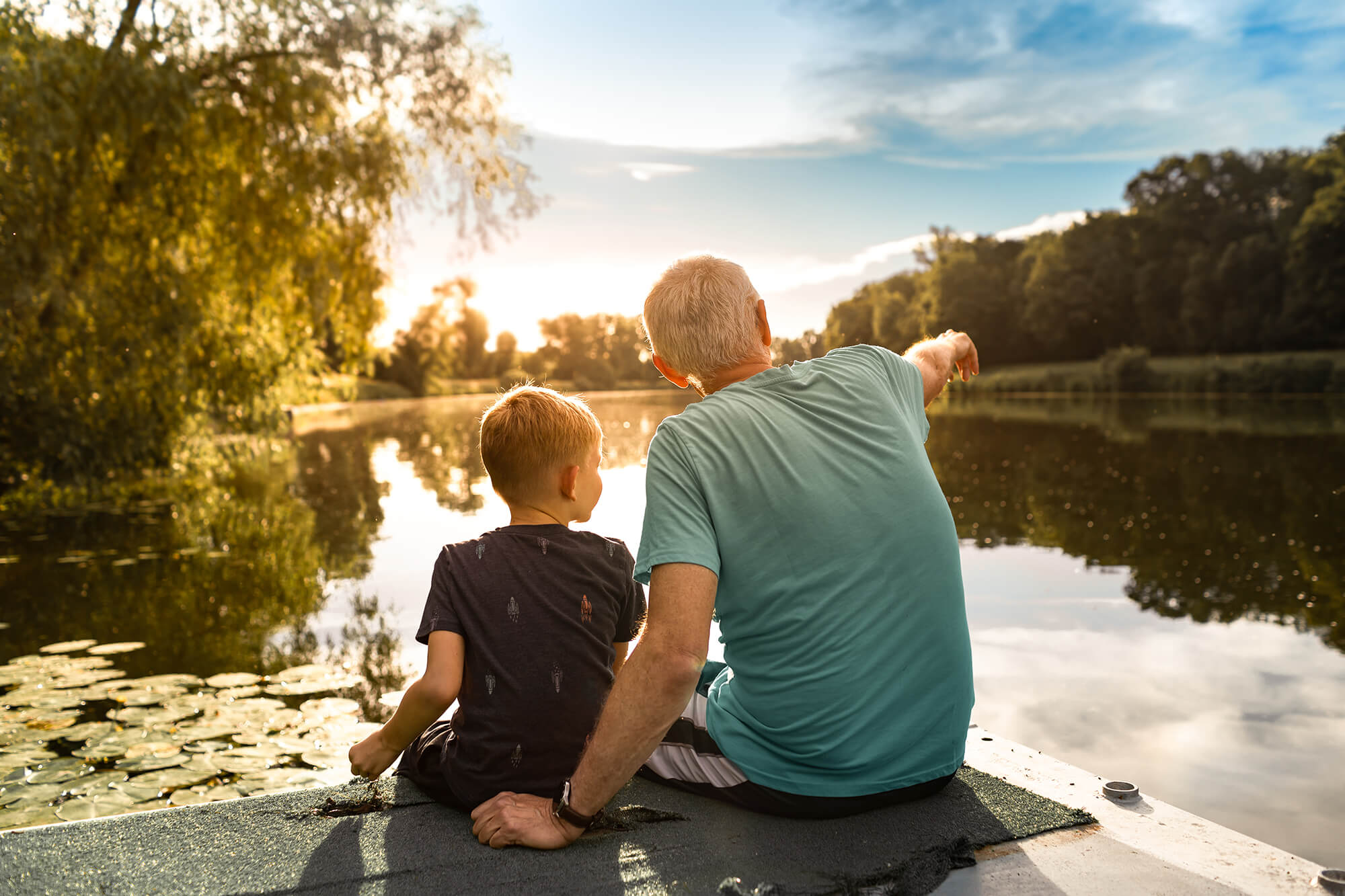 Grandfather and grandson sitting together outdoors on a dock